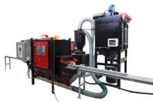 Industrial inline sandblaster with a conveyor belt, control panel, large extraction unit, and connecting hoses in black and red—designed for automated pass-through sandblasting and efficient surface treatment.