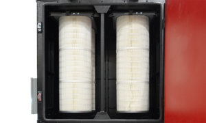 Close-up view of two large cylindrical air filters installed vertically inside a black and red enclosure. The filters are white and have a pleated design.