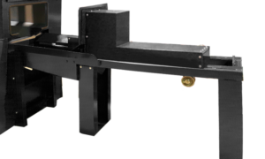 A close-up view of a black metal industrial machine with a rectangular frame, angular components, and a visible brass valve—ideal for sandblast cabinets or other parts handling solutions—set against a plain white background.